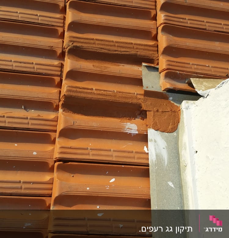 רעפים כתומים עם תיקון בטיט על הגג